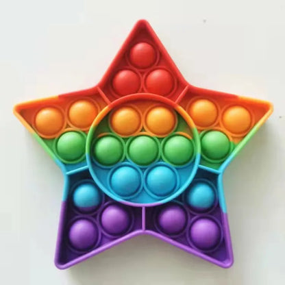 The Rainbow Pop Fidget Stress Toy by FidgetFuns is a star-shaped pop-it with a circular center, both in a rainbow gradient. Ideal for stress relief, this vibrant toy stands out on its plain white background.