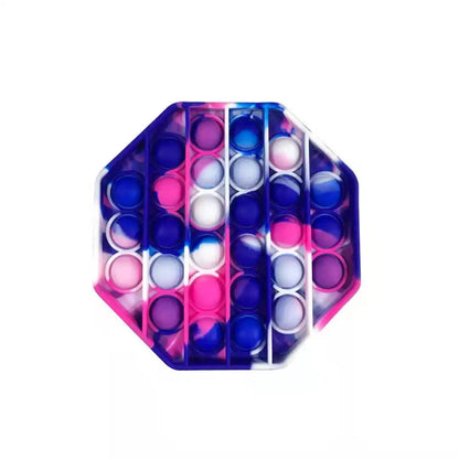 The FidgetFuns Rainbow Pop Fidget Stress Toy features an octagonal design with pink, purple, blue, and white gradient stripes. Its semi-pressed silicone bubbles offer sensory satisfaction for stress relief, all set against a plain white background.