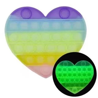 The Rainbow Pop Fidget Stress Toy by FidgetFuns, a heart-shaped push bubble dimple in rainbow colors, glows green in the dark for sensory satisfaction and stress relief.